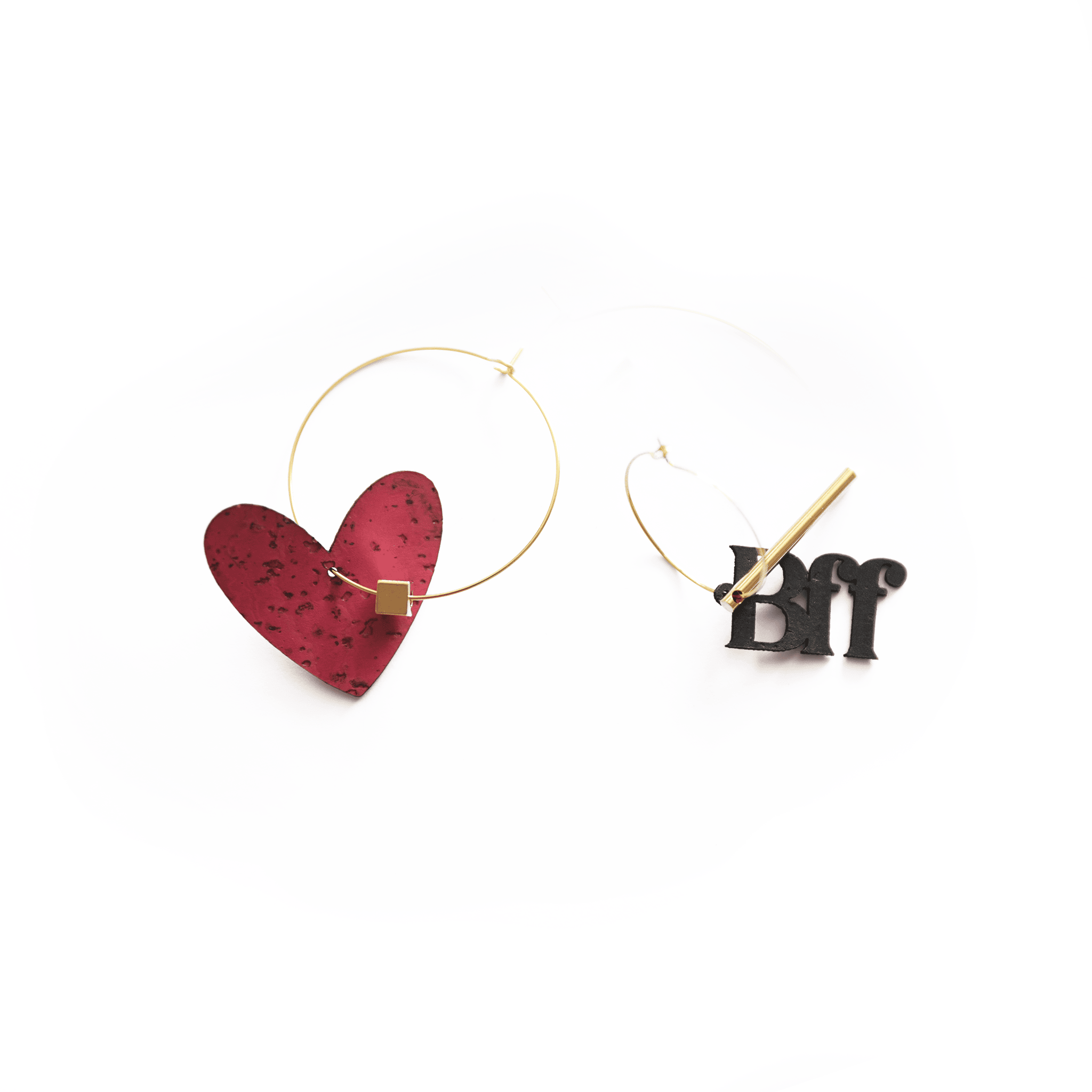 Paire de boucles d’oreilles dépareillées : une créole dorée avec un cœur rouge en liège, et une autre avec la breloque "BFF" noire accompagnée d’un cylindre doré.