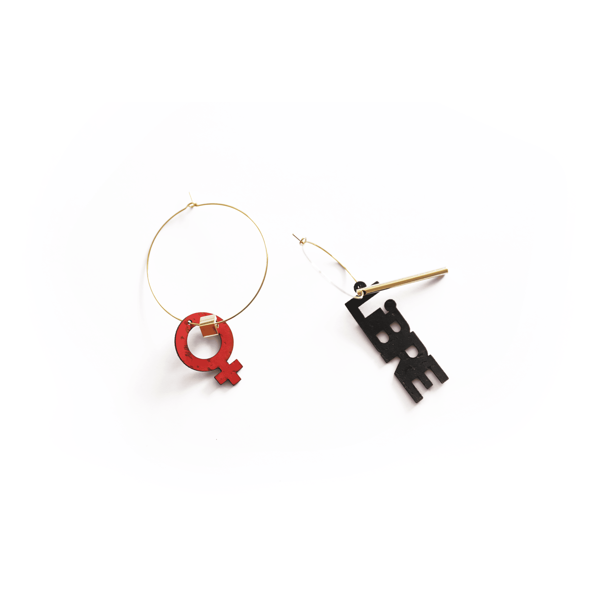 Paire de boucles d’oreilles asymétriques avec symbole féminin rouge et mot "LIBRE" en noir, montées sur créoles dorées.