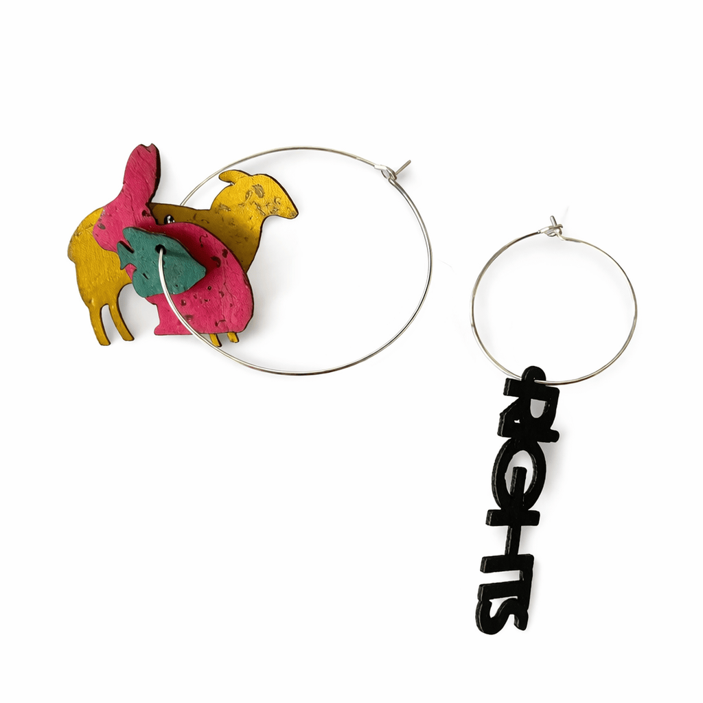 Les boucles d oreilles depareillees “Animal Rights” affichent clairement la couleur : un bijou engagé, graphique et assumé. D’un cote, une composition d’animaux en liege colores. De l’autre, le mot “rights” en noir. Un contraste fort pour porter un message sans compromis.