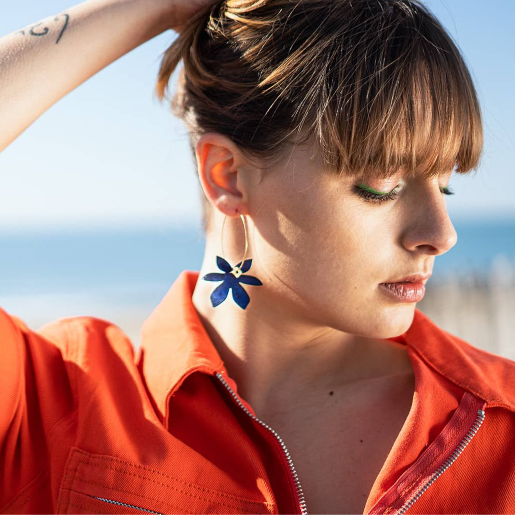 Boucles d oreilles fantaisie femme portées en extérieur avec créole dorée et breloque fleur bleu indigo, bijou original coloré style été bord de mer