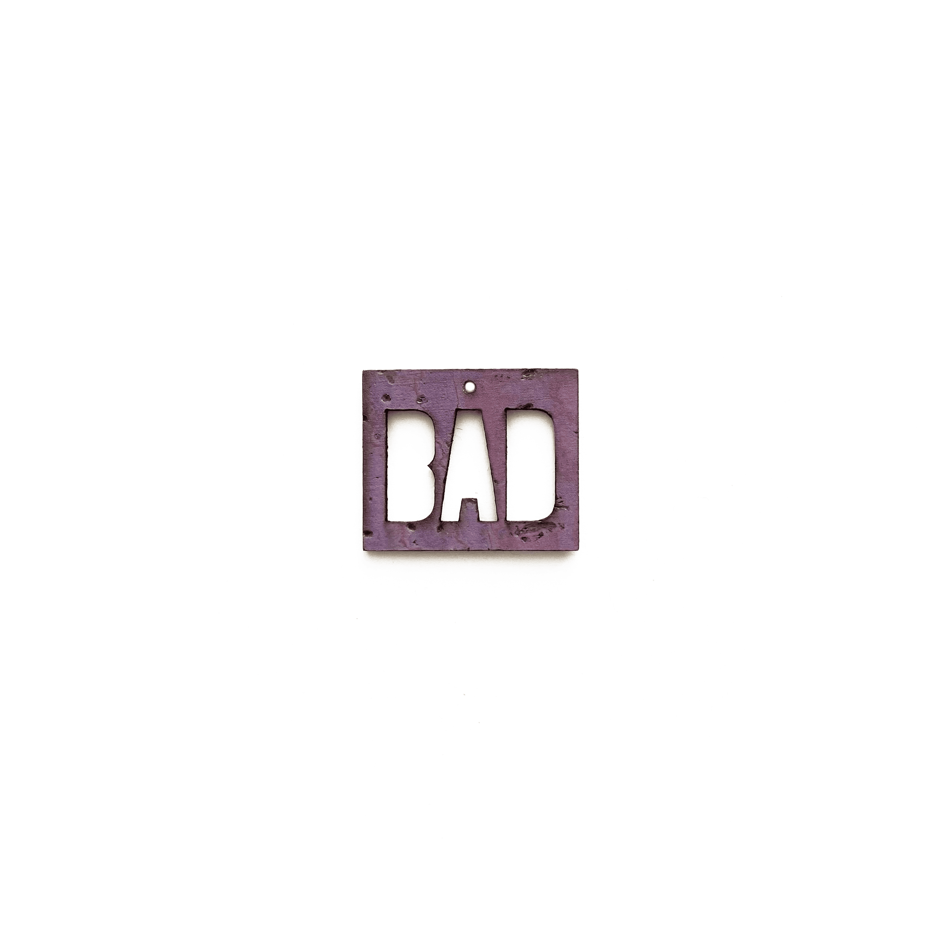 Breloque violette gravée "BAD" en métal éthique, vue de face sur fond blanc, bijou personnalisable de la marque Matcha Paris.