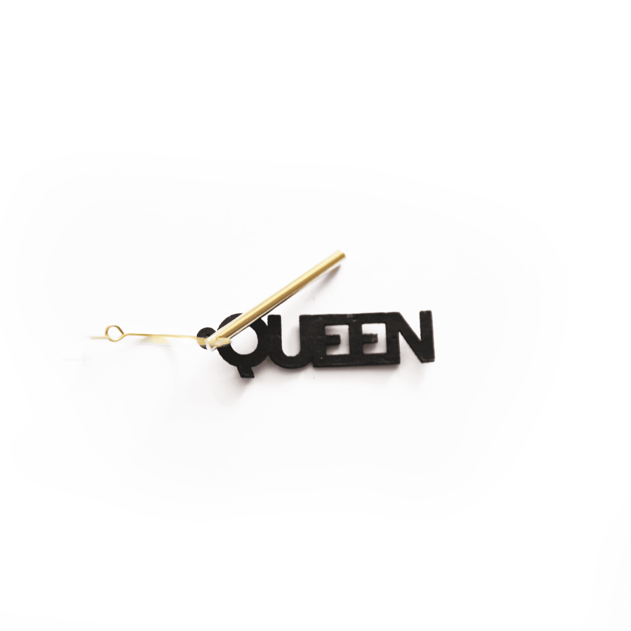 Breloque noire avec inscription "QUEEN", montée sur créole dorée, bijou interchangeable et personnalisable Matcha Paris, fabriqué en matériau vegan.