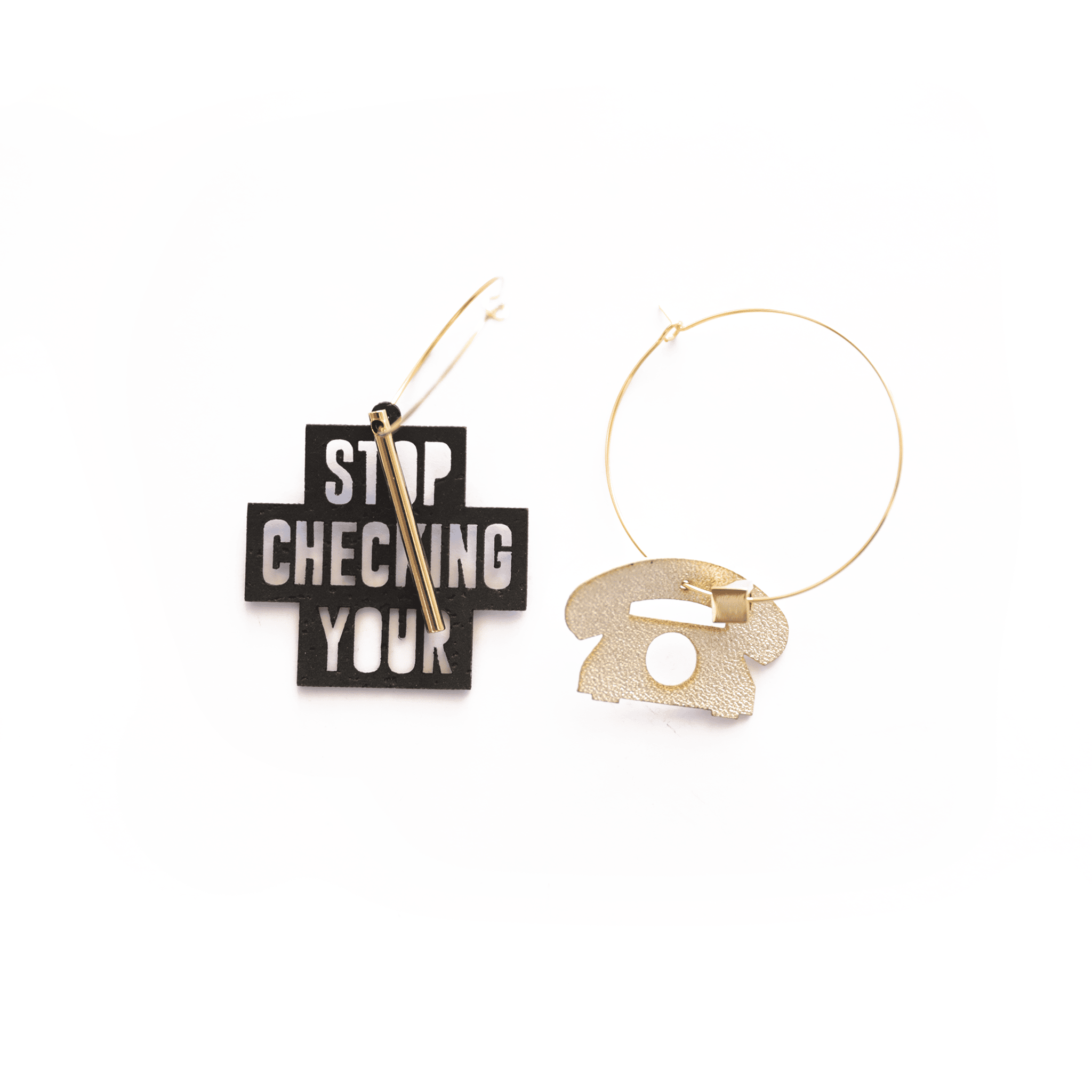 Boucles d’oreilles asymétriques dorées : une créole avec breloque noire inscrite "Stop Checking Your Phone" et une créole assortie avec pendentif doré en forme de téléphone rétro. Bijoux originaux, personnalisables et fabriqués en France.