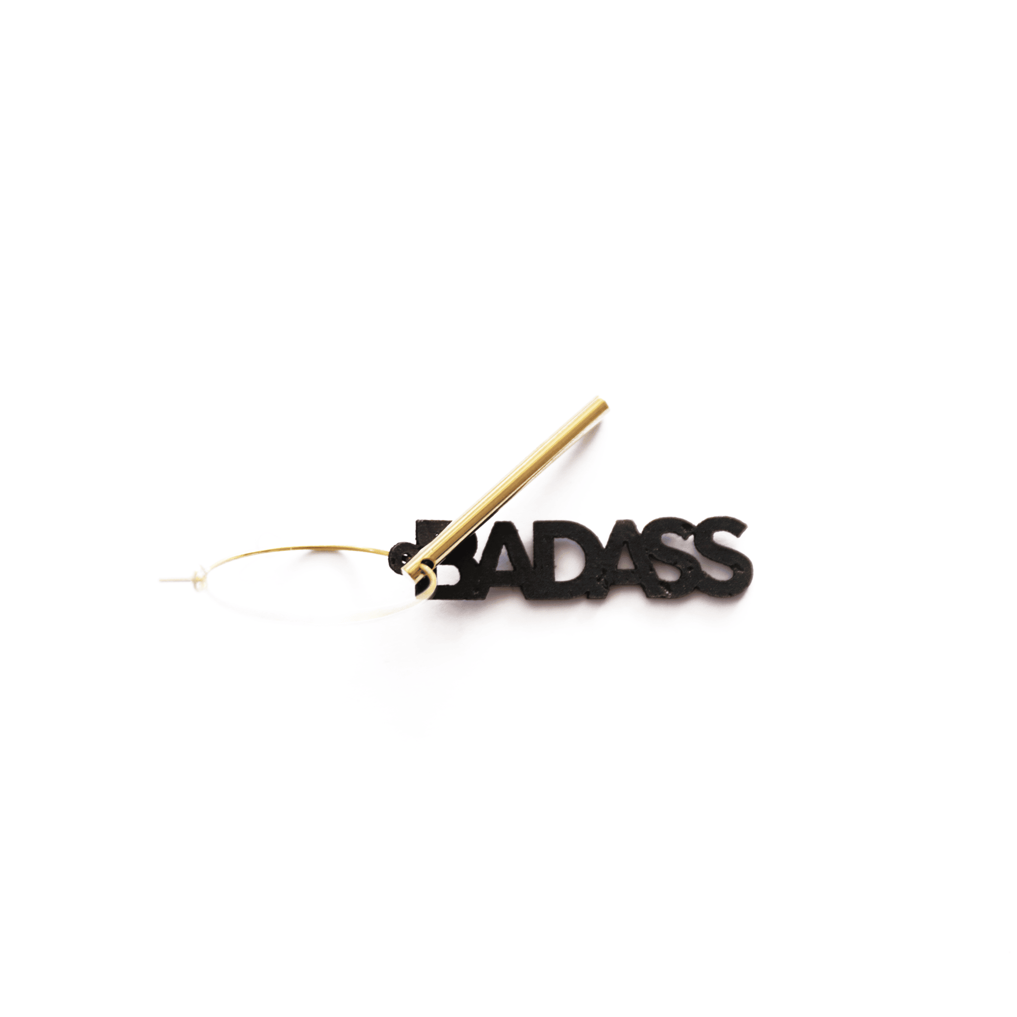 Breloque noire "BADASS" en matériau vegan, bijou personnalisable et fabriqué en France, photographiée sur fond blanc.