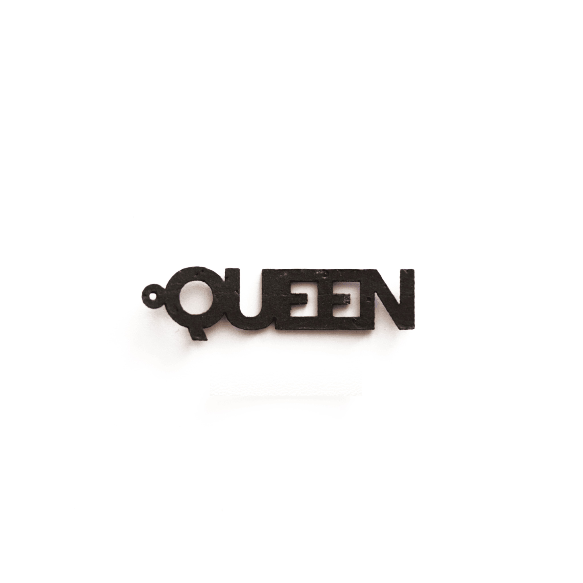 Zoom sur la breloque noire "QUEEN" montée sur créole dorée, bijou en matériau vegan, personnalisable et fabriqué en France par Matcha Paris.