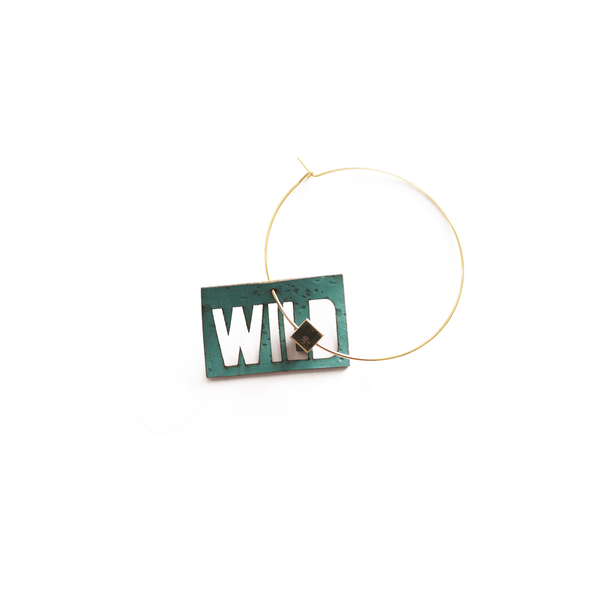 Breloque turquoise en liège vegan avec le mot "WILD" découpé, photographie en gros plan sur fond blanc, bijou interchangeable fabriqué en France par Matcha Paris.