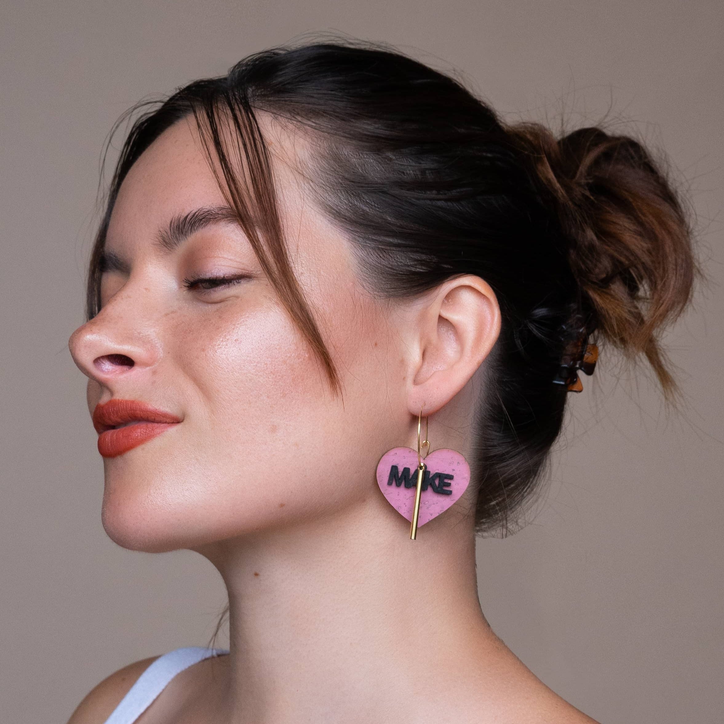 Femme portant les creoles Make Love Not War de Matcha Paris, boucles doreilles roses en liege recycle, bijou vegan et fabrique en France.