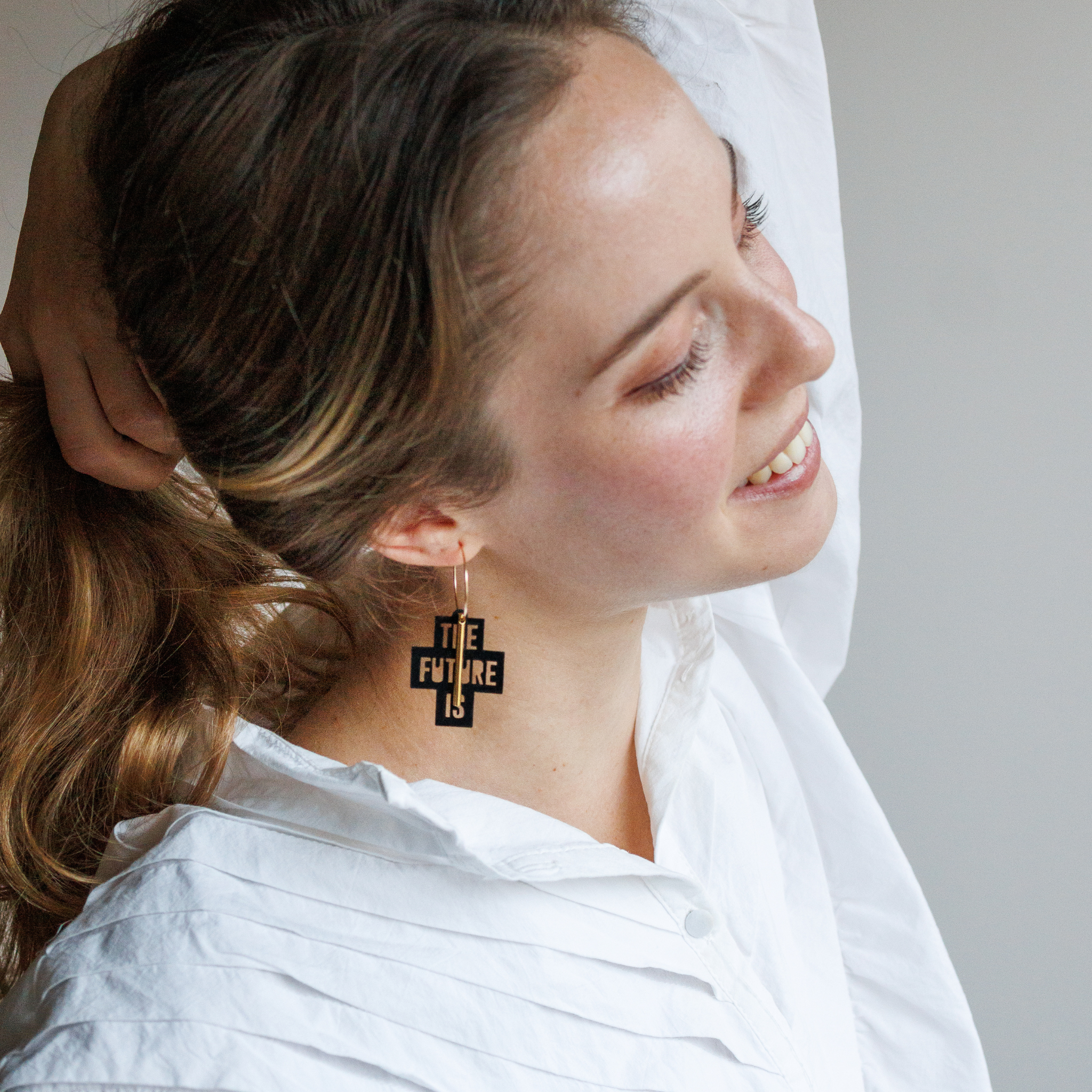 Femme portant les creoles The Future Is Female de Matcha Paris, boucles doreilles dorees en matiere recyclee, bijou vegan et fabrique en France.