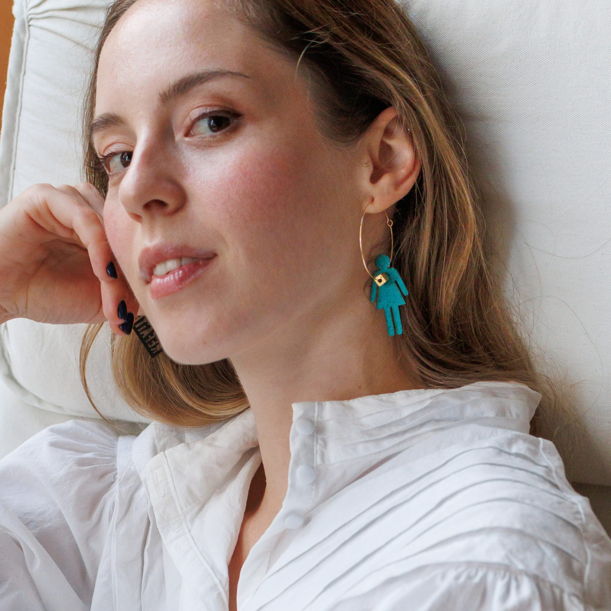 Femme portant les creoles Who Run The World de Matcha Paris, boucles doreilles bleu turquoise en matiere recyclee, bijou vegan et made in France.