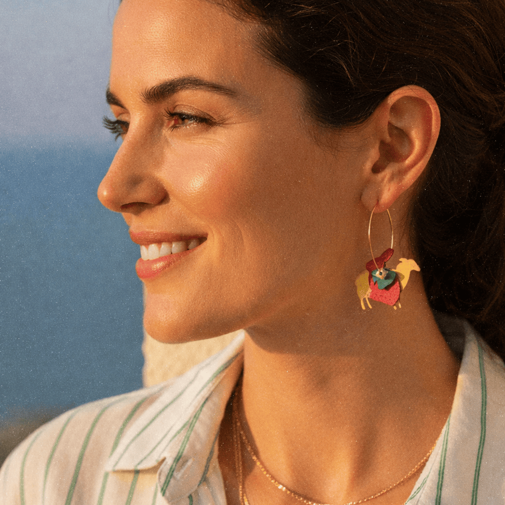 Femme portant des creoles depareillees Animal Rights avec silhouettes d animaux colores, bijoux engages vegan en laiton dore, photo lifestyle au soleil.