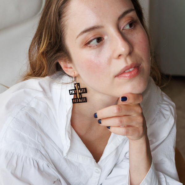 Femme portant une créole noire "Ni parfaite ni refaite" de Matcha Paris, bijou féministe fabriqué en France.