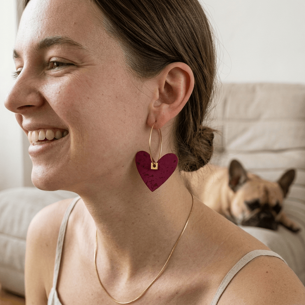 femme souriante portant boucle d'oreilles dépareillées coeur rose acier inoxydable avec chien en arrière plan moment naturel