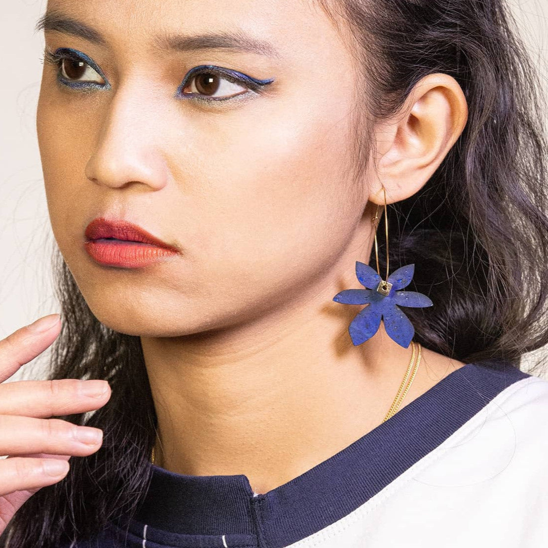 femme portant boucles d’oreilles dépareillées fleur bleu indigo créoles asymétriques en acier inoxydable look élégant et moderne