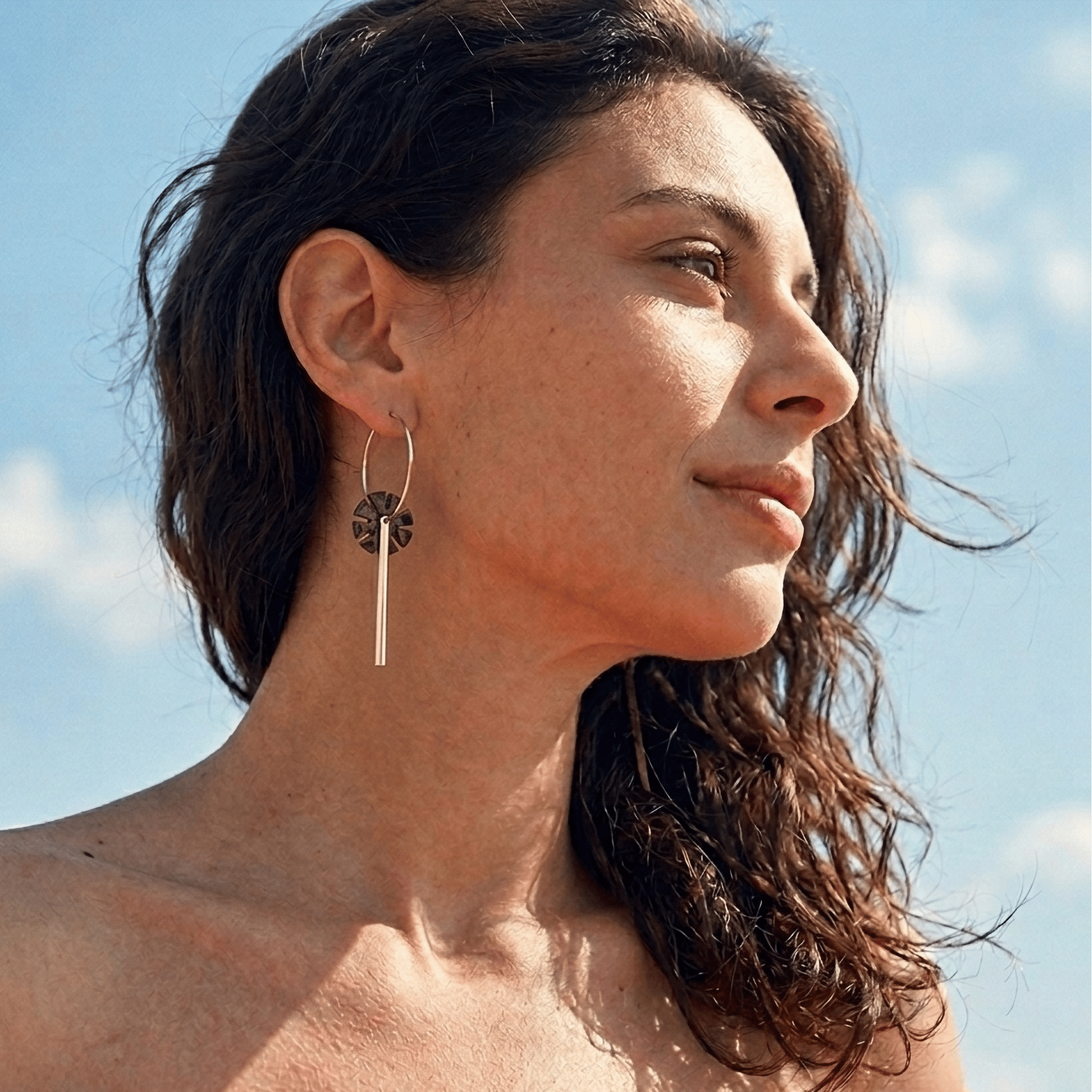 femme portant boucles d’oreilles dépareillées léopard asymétriques avec créole et tige longue look été ciel bleu style mode