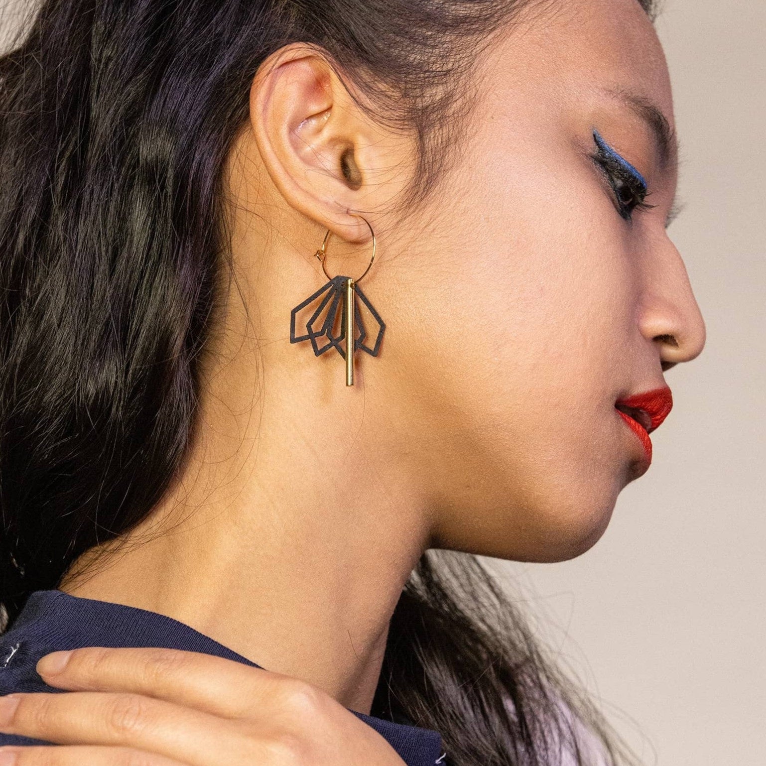 femme portant boucles d’oreilles dépareillées noires créoles asymétriques avec design graphique et tige dorée look moderne et élégant