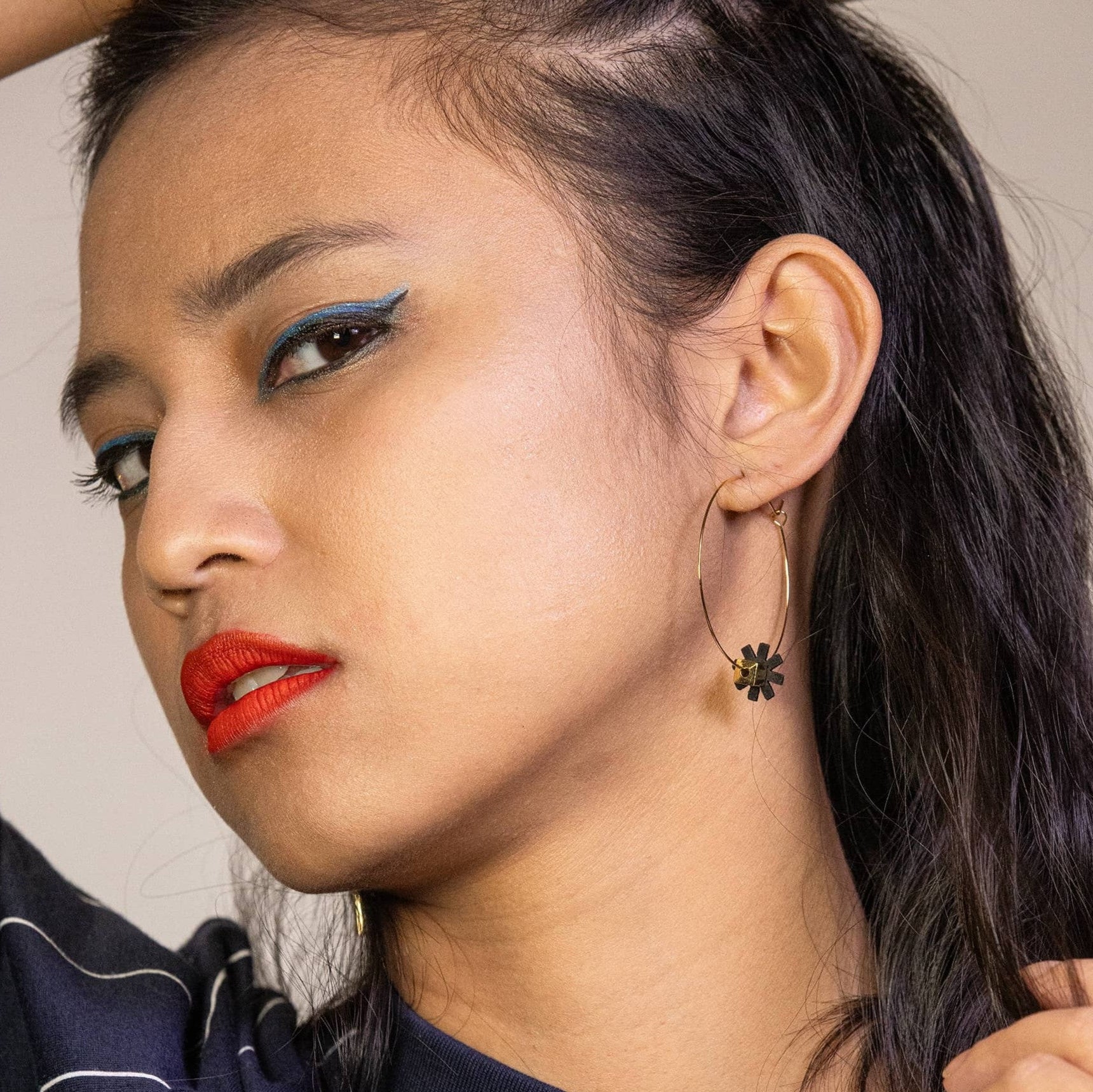 femme portant boucles d’oreilles dépareillées noires créoles asymétriques avec fleur graphique en acier inoxydable look élégant et moderne