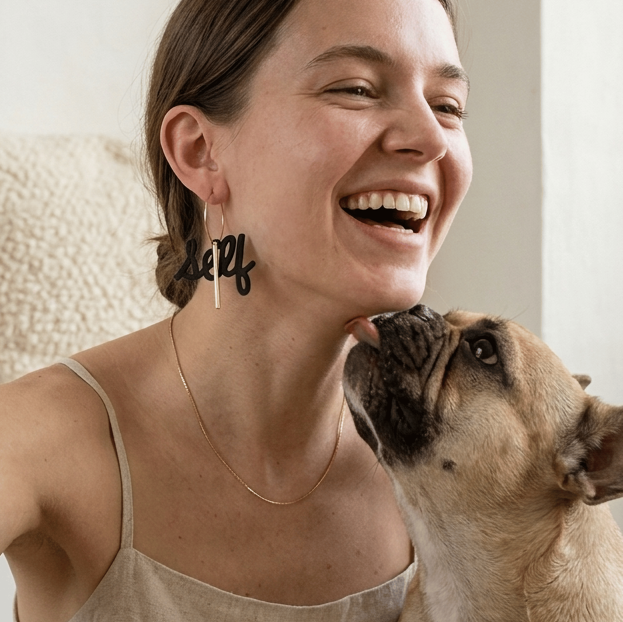 femme souriante portant boucle d oreilles dépareillées self love avec chien moment complice bijoux asymétriques noir