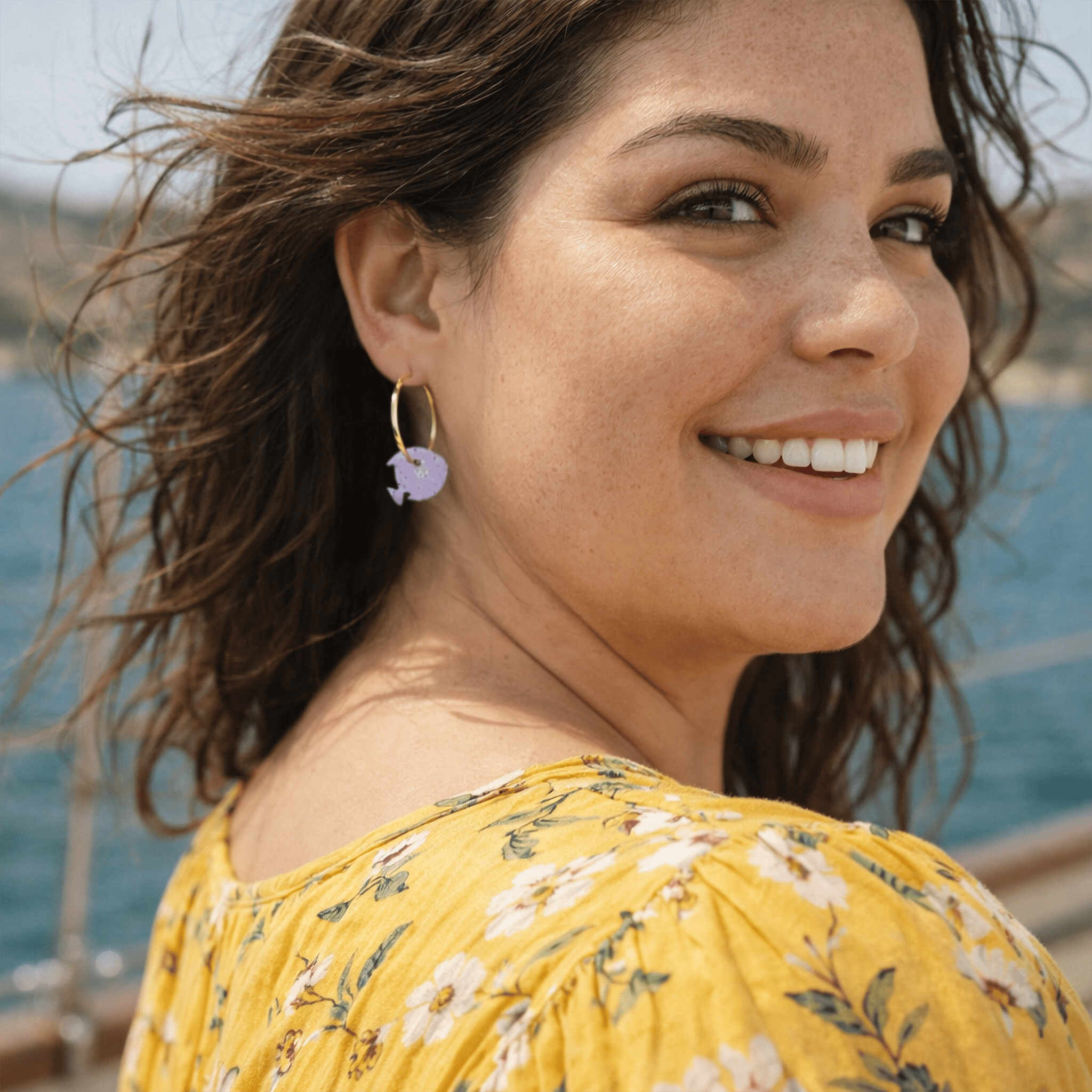 femme portant boucles d oreilles depareillees nemo violet sur creoles fines bijou artisanal fait main style ete bord de mer
