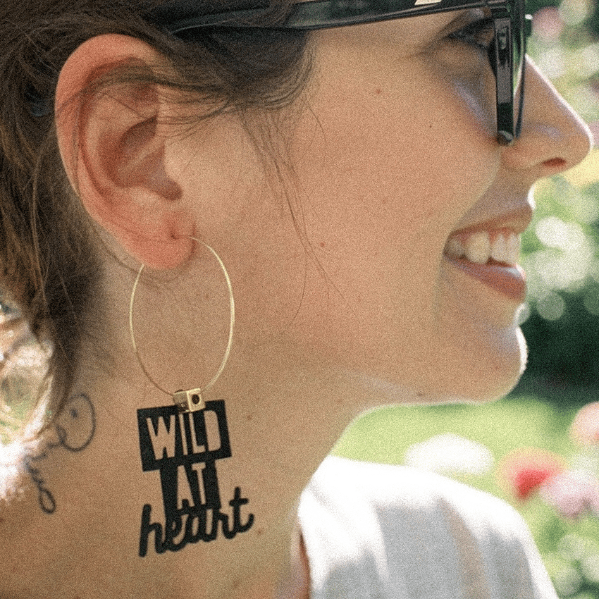 Boucle d’oreille Sagittaire portée par une femme, créole dépareillée avec message Wild at heart.