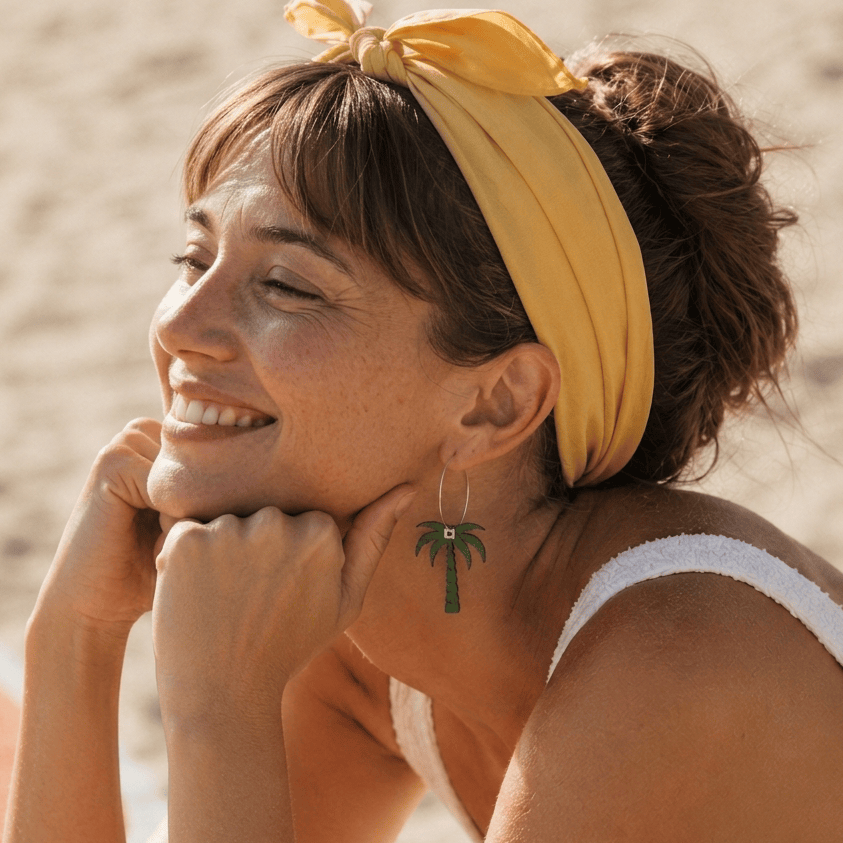 Boucles d'oreilles dépareillées Voyage Voyage portées à la plage — créole palmier liège vert Matcha Bijoux