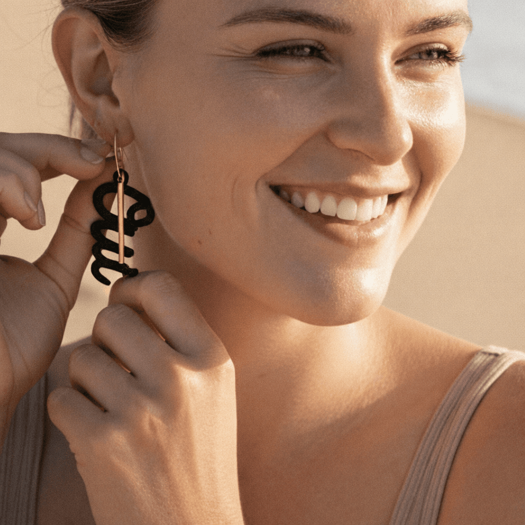 Modele femme blonde portant des creoles depareillees Oui en laiton dore, boucles d oreilles asymetriques graphiques et modernes.