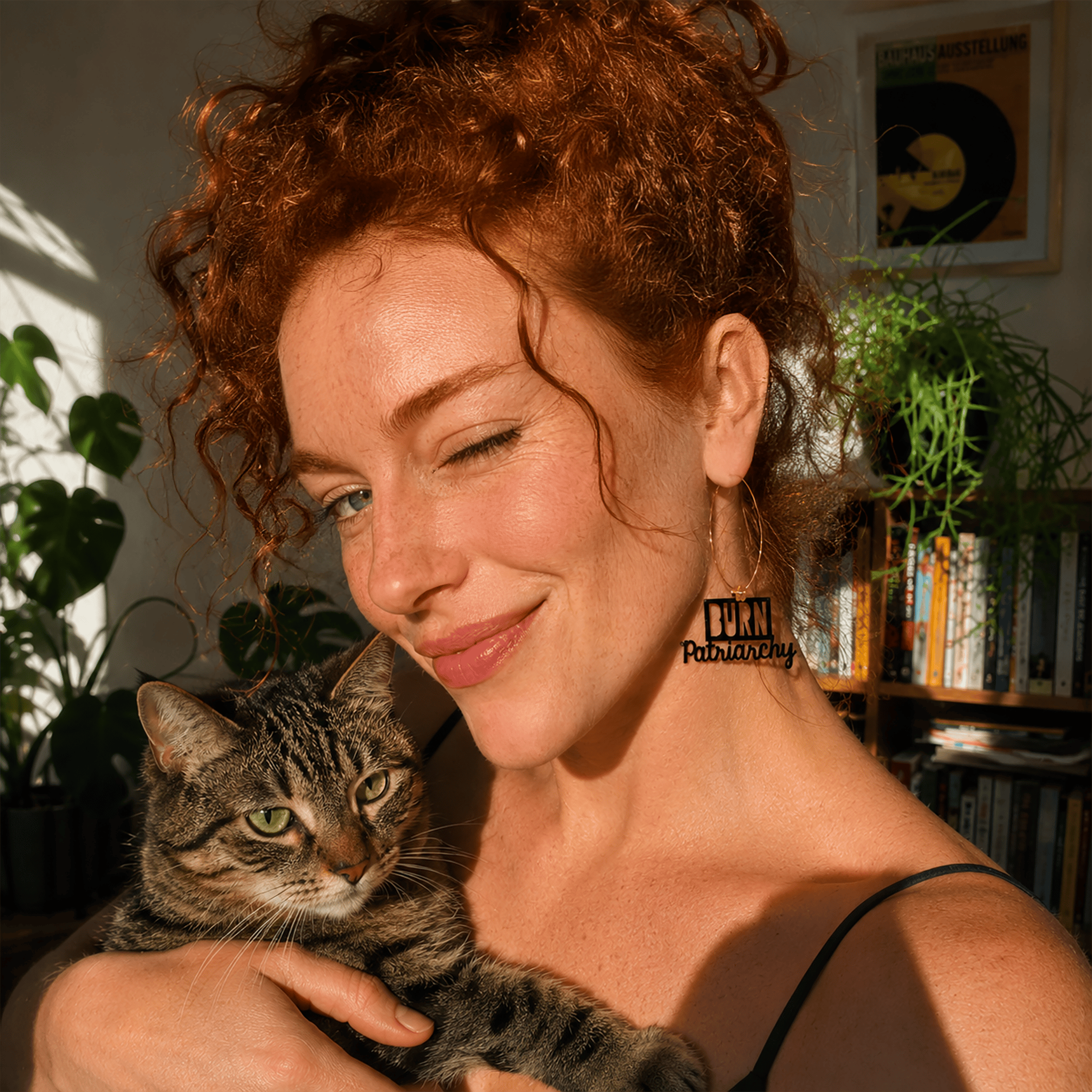 Boucles d'oreilles dépareillées et colorées féministes "Burn patriarchy" sur jeune femme avec chat
