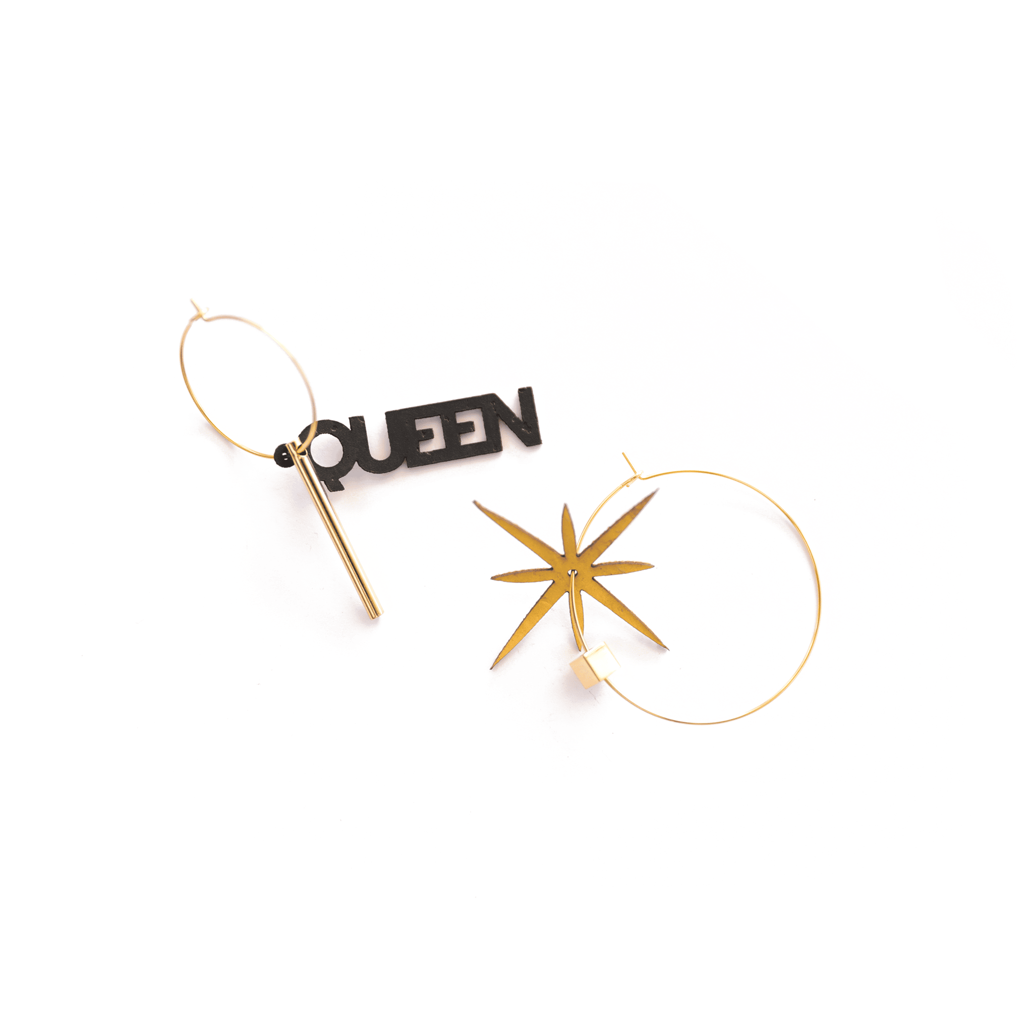 Paire de créoles dorées asymétriques : une avec le mot "QUEEN" en liège noir et barre dorée, l’autre avec une étoile dorée à huit branches. Bijoux éthiques, fabriqués en France, au design affirmé et personnalisable.
