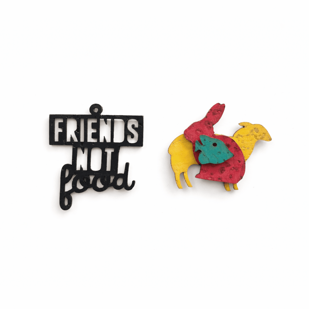 Packshot breloques Friends Not Food vegan sur fond blanc, message noir et silhouettes d’animaux colorées en matieres vegetales.